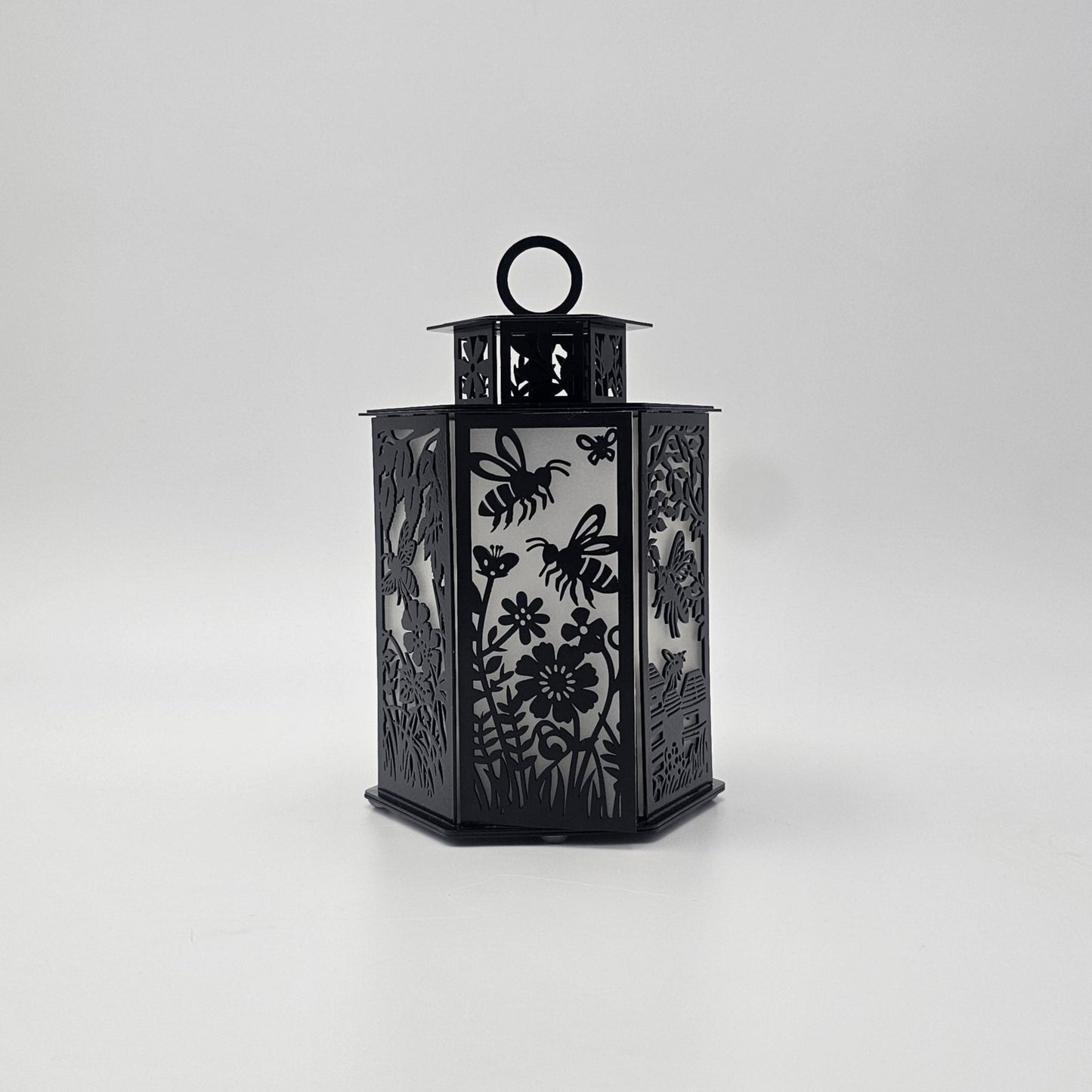 Bees and Butterflies Metal Lantern. Measures 9 Inches High x 6 Inches Wide. Comes in either Powder Coat Gloss Black or Colored-Rustic. Battery operated votive, riser cup and battery included. Votive has on off switch.