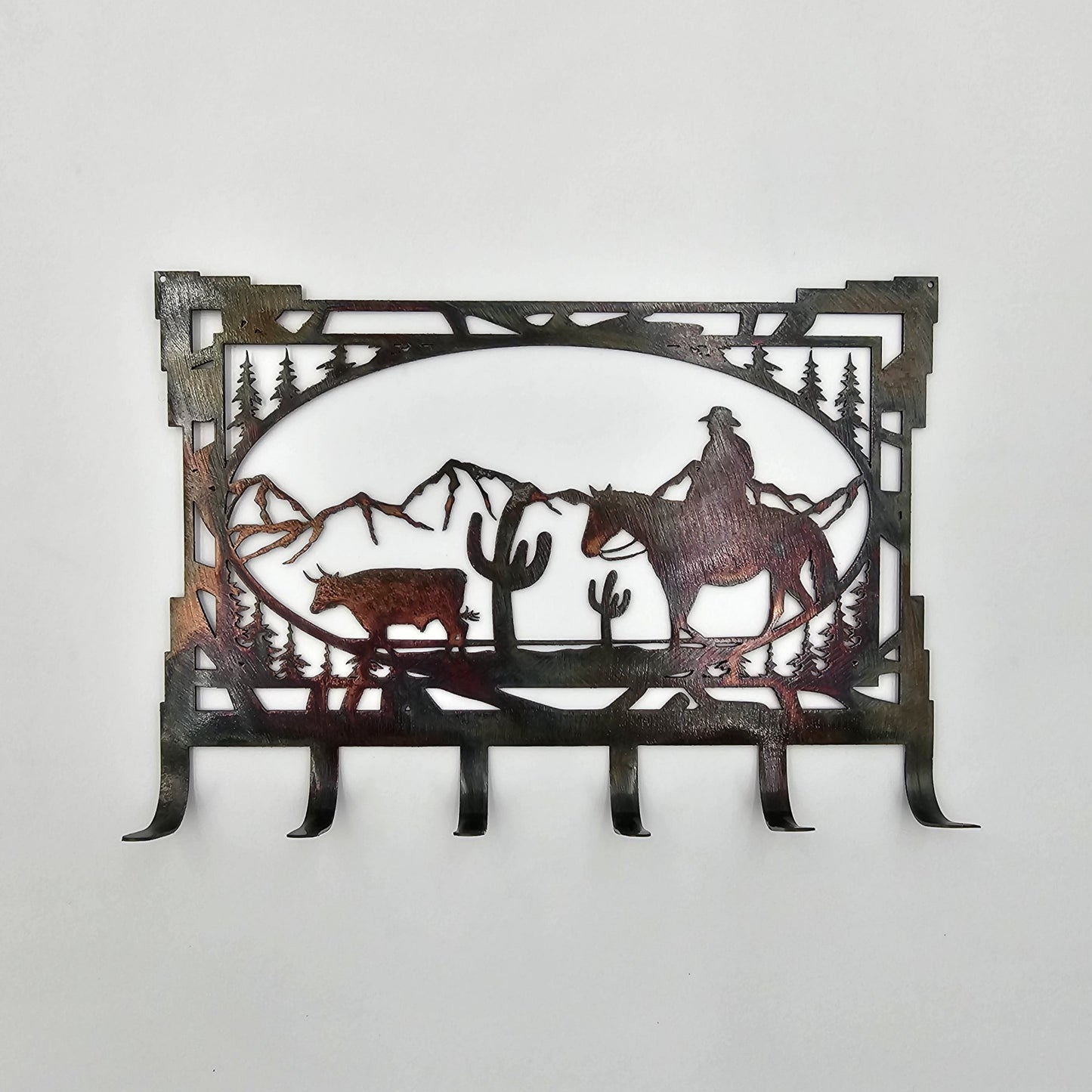 Cowboy riding his horse through the mountains hearding a Bull
