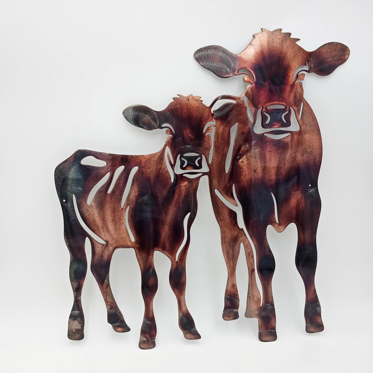 Rustic Metal Cow Wall Hanging. Two Sizes available: Medium measures 12 Inches Wide x 11 Inches High. Large measures 20 Inches Wide x 19 Inches Wide. Five colors available: Colored-Rustic, Flat Black, Hammered Black, Hammered Beige, Bare Metal. Sprayed with automotive clear coat. Hangs via two holes in cows. Use two nails to hang not included.