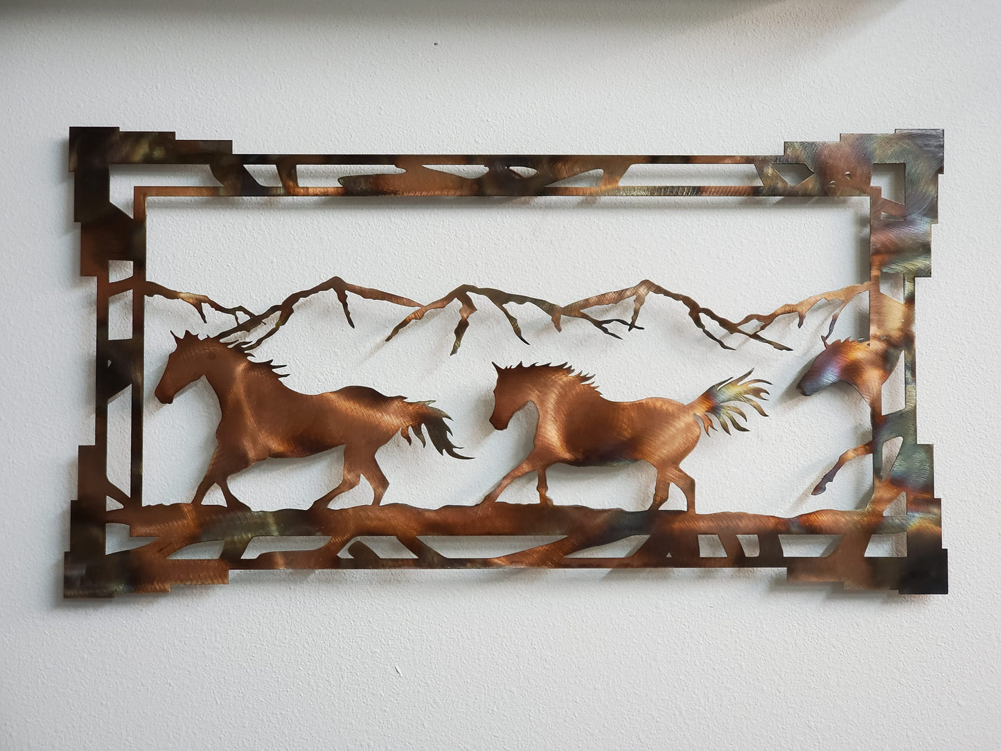 Southwest Style Horse Metal Wall Hanging framed in aztec frame.. Made from 18 gauge cold rolled sheet metal. Two sizes available 16 inches high by 30 inches wide or 11 inches high by 20 inches wide. Available in four colors. Colored which is very rustic looking. Black, hammer tone, and bare metal. Sprayed with a layer of varathane. Brackets on back for easy hanging. Hangs via nails not included. Gift wrapping available at checkout.