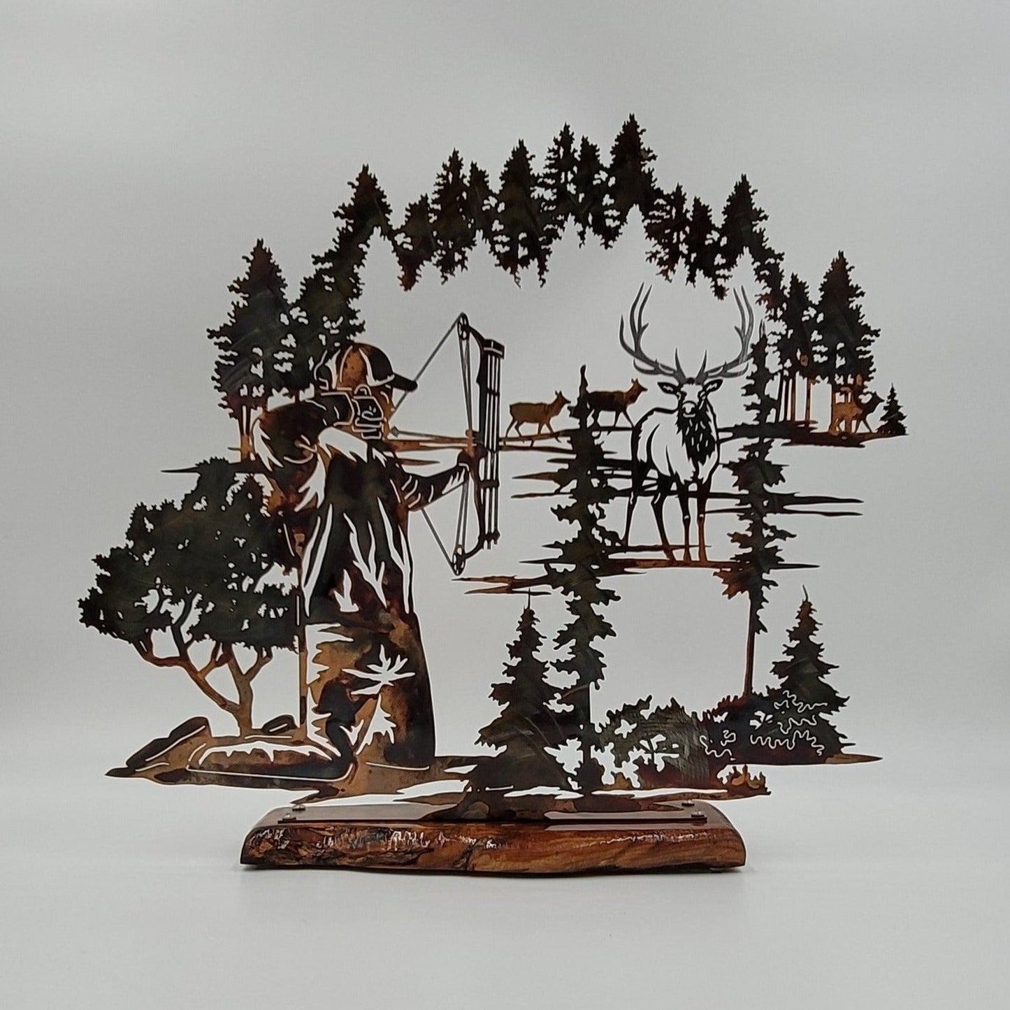 Bow Hunter Hunting Elk Metal Shelf Sitter measures 16" H x 8.5" W x 18 gauge thick. Sits on top of a piece of wood that measures 13.5" L x 7.5" W x 1/2" thick. Available in four colors; Colored-Rustic, Black, Hammer Tone, Bare Metal. This is the colored rustic version. Sprayed with several layers of Varathane.