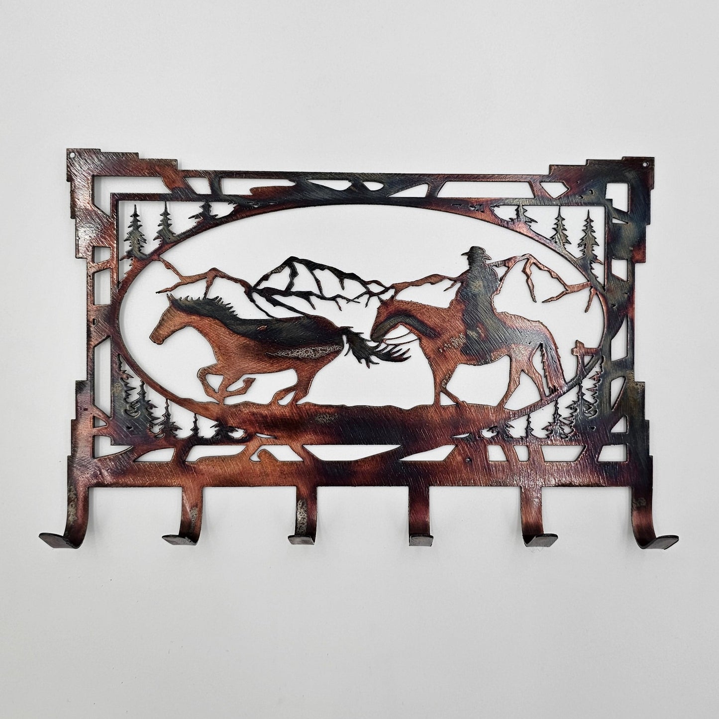 Cowboy Key Rack Measures 8" Wide x 5.5" High and constructed of 18-gauge steel, key rack features 6 hooks and can be purchased in four colors: Colored-Rustic, Black, Hammer Tone, and Bare Metal. A hand-ground texture is applied to the colored-rustic version and a thick layer of Varathane is applied for protection to all versions. Colored-Rustic versions may have slight variations due to the coloring process, but we do our best to replicate what you see in the photos. Gift Wrapping available at checkout.